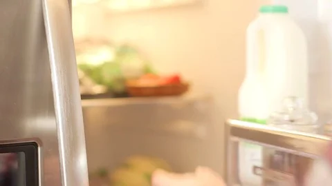 Young man in a checked shirt opening the fridge door in the kitchen Stock Footage 74605591