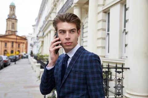 Young man in checked suit using phone in street, waist up Stock Photos