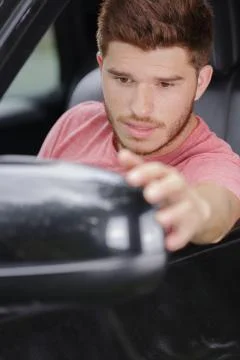 Young man checking car side mirror Stock Photos