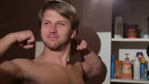 Young man checking his muscles in front of the mirror in bathroom. Stock Footage 76116522