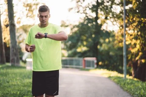 Young man checking his watch after a run outside Stock Photos