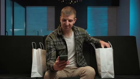 Young man checking orders for goods and packaging shopping bag sitting on the Stock Footage 225657675