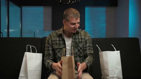 Young man checking orders for goods and packaging shopping bag sitting on the Stock Footage 225657991