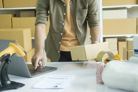 Young man checking parcel address using laptop. Stock Photos