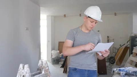 Young man checking project documentation in apartment during repair works Stock Footage 250500234