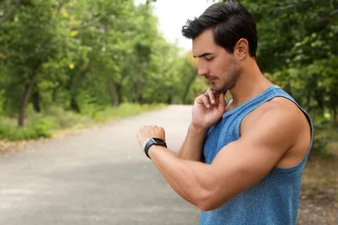 Young man checking pulse after training in park. Space for text Fotos de archivo