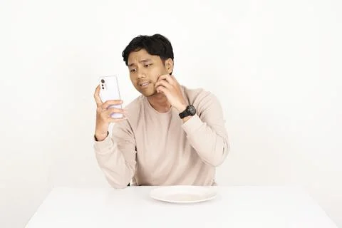 Young man checking skin problems while looking at smartphone Stock-Fotos