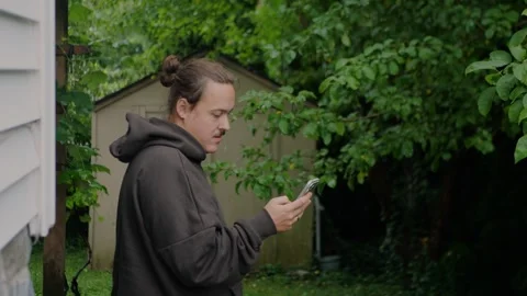 Young man checking smartphone in a natural garden... 스톡 동영상 339101753