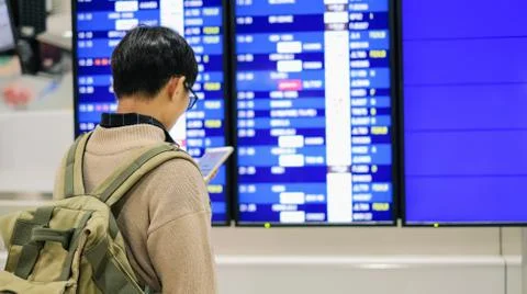 Young man checking timetable over airline board for travel at the airport Foto stock