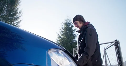 Young man checking under the bonnet of his car 库存影片 104985364