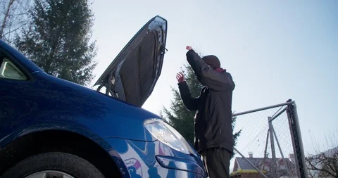 Young man checking under the hood of his car Stockbeeldmateriaal 104984473