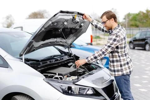 Young man checking under the hood of his car to figure out what the problem i Stock Photos