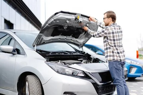 Young man checking under the hood of his car to figure out what the problem i Stock Photos
