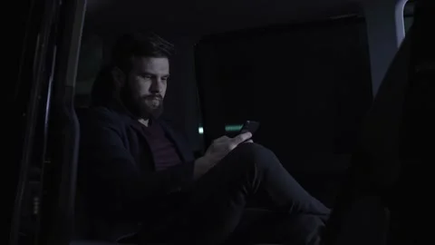 Young man checks his mobile phone before the trip at vip van shuttle Stock Footage 144688201