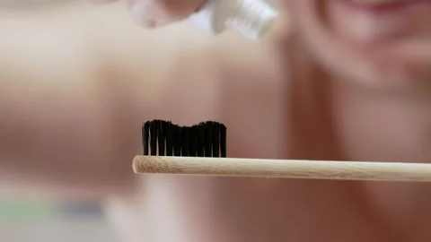 A young man with a cheeky smile squeezes toothpaste onto a toothbrush Stock Footage 212050761