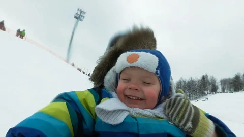 A young man with a cheerful boy with a roller coaster ride in the winter on the Video stock 100833849