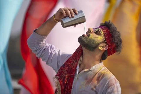 A young man cheerfully drinking bhang during holi celebrations Stock Photos