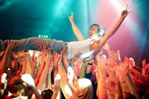 A young man cheering as he crowd surfs at a concert. This concert was created Stock Photos