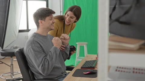 Young man cheering at keyboard while woman photographer leans over holding .. Stock Footage 337368992
