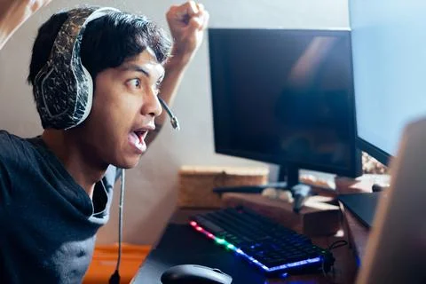 Young man cheering while gaming on computer Stock Photos
