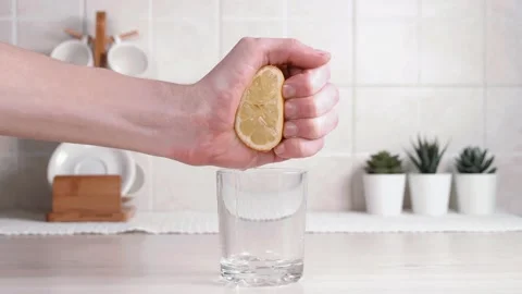 Young man, chef squeezes lemon juice into a glass in the kitchen on the table Stock Footage 141119933