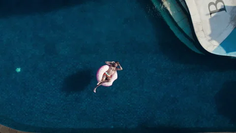 Young man chill swim in infinity pool with inflatable donut rubber ring Stock Footage 269112866