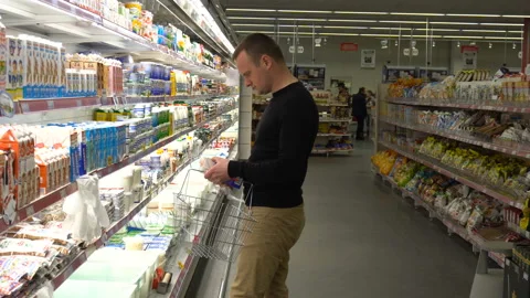Young man chooses and buys milk at the supermarket. Stock Footage 89593151