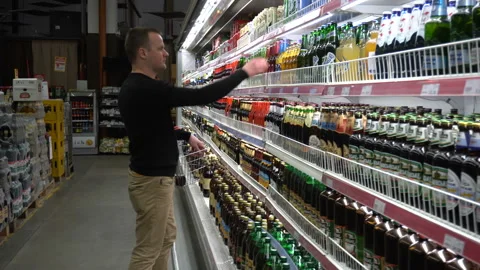The young man chooses a beer for bbq party with friends in the supermarket. Stock Footage 89591768