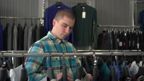Young man chooses clothes in the store. Clothing store. 스톡 동영상 140058382