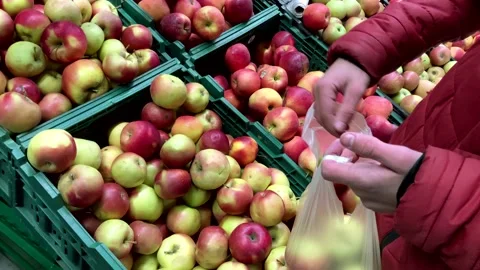 A young man chooses fresh apples in a supermarket or market. chooses fruits in Stock Footage 229809147