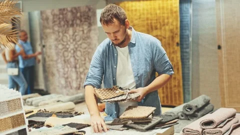Young man choosing carpet samples in store Stock Footage 313099009