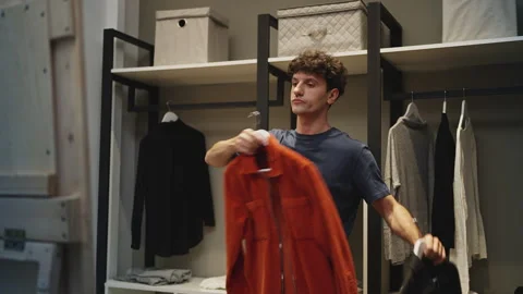 Young man choosing jackets in front of mirror, getting ready to leave home Stock Footage 337908029