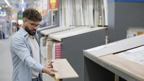 Young man choosing laminate flooring in hardware store Stock Footage 336965213