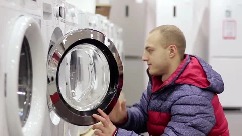 A young man choosing a washing machine in a home appliance store Stock Footage 85705486