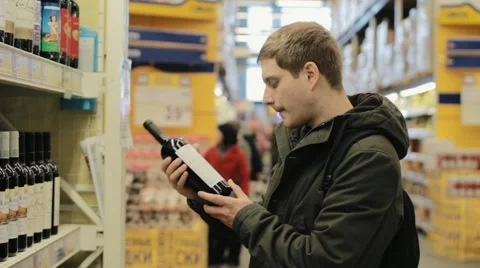 Young man choosing wine in the store Video stock 62454792