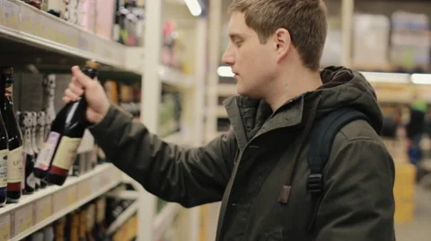 Young man choosing wine in the store Stock Footage 62458144