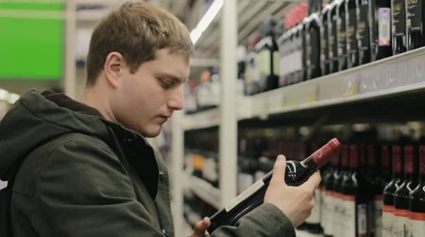 Young man choosing wine in the wine store Stock Footage 62459321