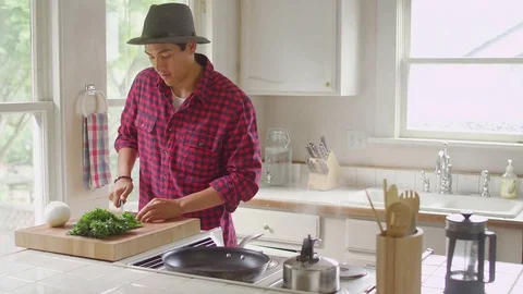 A young man is chopping vegetables and then hugs his girlfriend Stock Footage