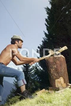 Young man chopping wood, side view Stock Photos