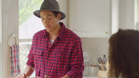 Young man chops vegetables while talking to his girlfriend Stock Footage 74357848