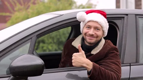 Young man in Christmas Santa hat showing thumbs up while driving car. Stock Footage 318745603