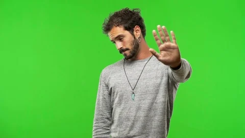 Young man on chroma green screen putting hand in front Stock Footage 97706191