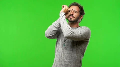 Young man on chroma green screen making the gesture of a spyglass Stock Footage 97706328