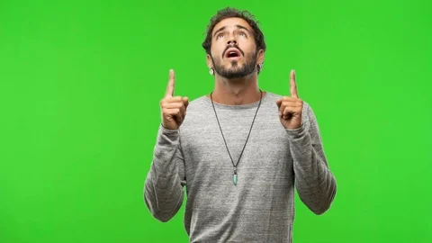 Young man on chroma green screen pointing up Stock Footage 97706391
