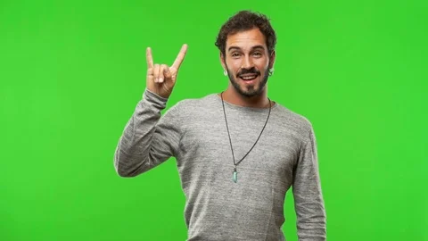 Young man on chroma green screen doing a rock gesture Stock Footage 97706413
