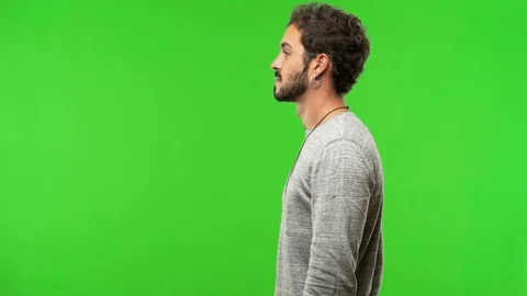 Young man on chroma green screen on the side looking Stock Footage 97706449
