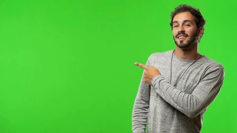 Young man on chroma green screen pointing to the side Stock Footage 97706460