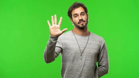 Young man on chroma green screen showing number five Stock Footage 97706617