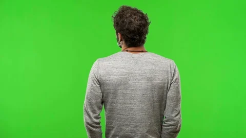 Young man on chroma green screen from behind, looking back Stock Footage 97706663