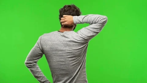Young man on chroma green screen from behind thinking about something Stock Footage 97706668